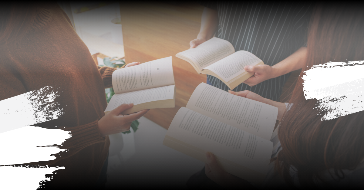 Three people holding books in a circle facing eachother